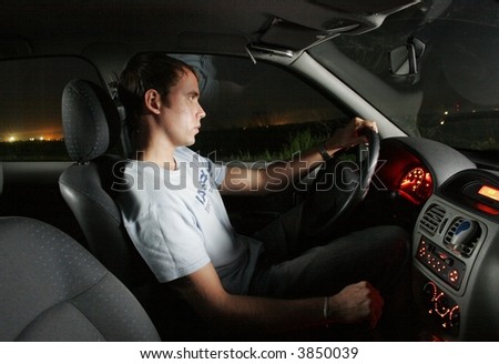 stock photo Young man driving a car at night Interior of a car