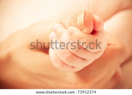 Baby\'s hand keeping mother finger, yellow tone