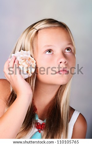 Young girl with shell listening to the sea