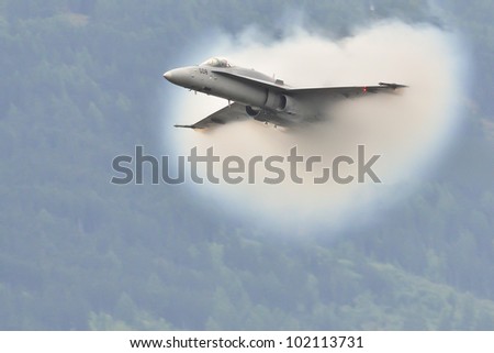 SION, SWITZERLAND - SEPTEMBER 17: Jet-plane breaks the sound barrier in front of the public during the Breitling Sion airshow on September 17, 2011 in Sion, Switzerland.