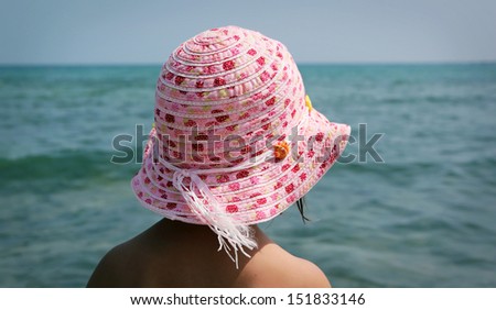Back of child with pink hat looking at the sea