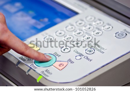 Copier Start - Finger pressing the start button on a multifunction printer or copier.