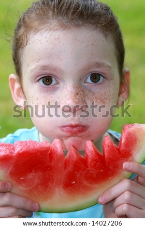 cute freckled girl eating watermelon with big bite
