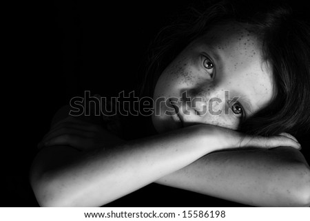 portrait of young girl with arms crossed using dramatic lighting for effect, black background, black and white photo