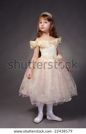 The little sad girl in elegant dress and tiara on a dark background