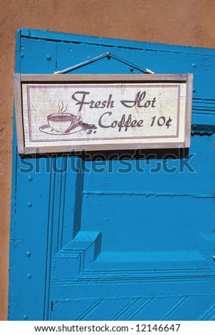 Vintage coffee sign hanging on turquoise door of cafe