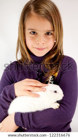Little girl 7 years old and white rabbit. White background.