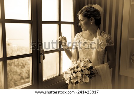 Nice girl the day of her wedding. The girl is looking outside the window in a cloudy day. Vintage effect.