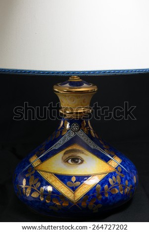 A ceramic masonic lamp , blue with golden decoration, with classical masonic symbols: square, compass, acacia; the triangle and the Eye