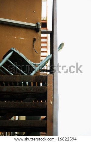 Metal chair holding door open at top of metal stairs