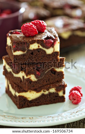 Cheesecake brownies with raspberry stacked on a plate
