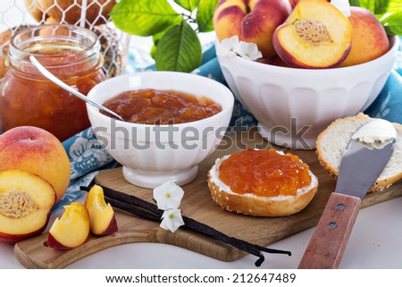 Vanilla peach jam in a bowl with vanilla sticks and fresh peaches