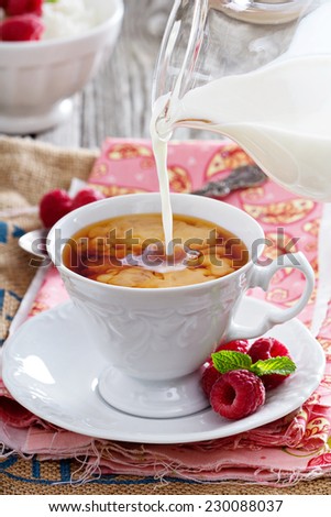 Cup of tea with milk pouring over from pitcher