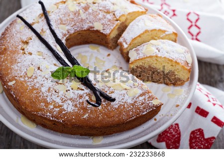 Vanilla, chocolate and almond cake on a cake stand powdered with sugar