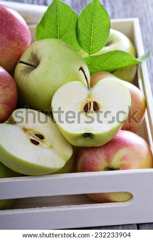 Fresh apples cut and whole in a wooden crate
