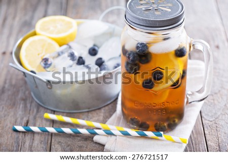 Ice tea in mason jar mug with lemon and blueberries refreshing in hot summer day