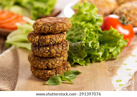Vegan burgers with lentils and pistachios stacked on a cutting board