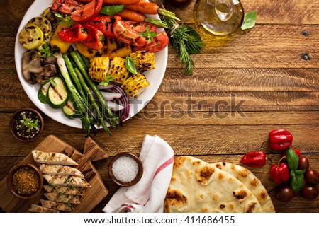 Grilled vegetables and chicken on wooden table overhead shot