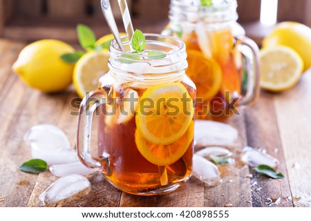 Iced tea with lemon slices and mint on rustic background