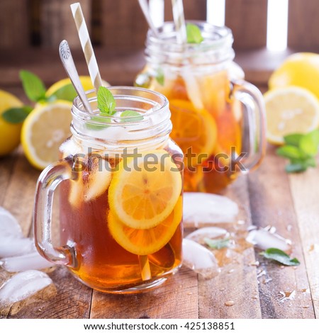 Iced tea with lemon slices and mint on rustic background