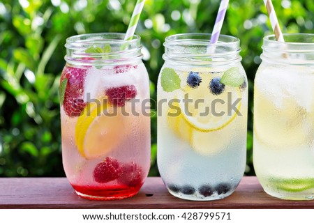 Variety of lemonade in mason jars with berries and fruits on the front porch