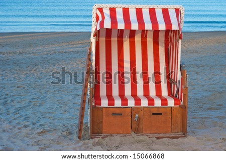 a striped german beach chair. Strandkorb. on the beach on a sunny day. used on cold and hot days