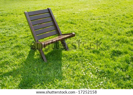one chair on green field on a sunny day