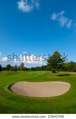 sand bunker on golf course with green grass and blue sky