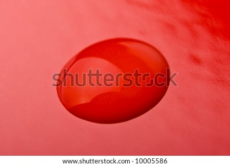 Macro of a single water drop on red background