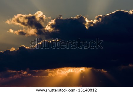 Sunset with beams of sunlight coming beneath the clouds