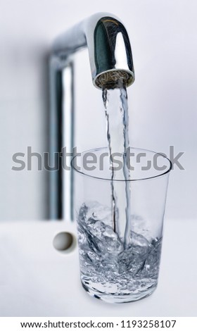 Filling water from the tap into a glass on white