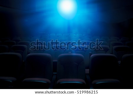 Dark film theater with projection light and empty seats