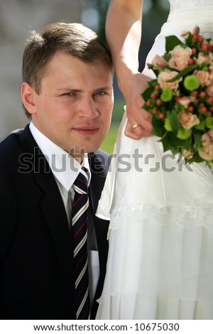 Handsome groom stood by wifes dress