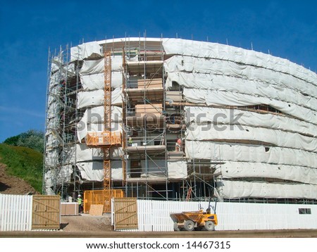 A general view of the exterior of a new modern building site development covered in scaffolding and cladding.