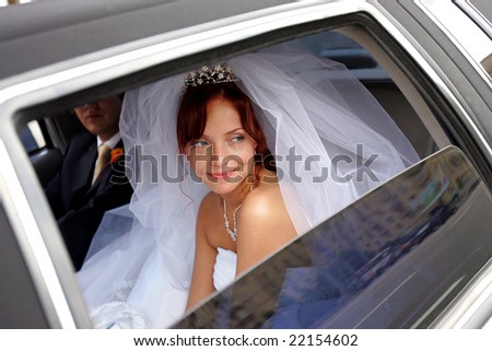 Smiling bride with groom in wedding car limousine.
