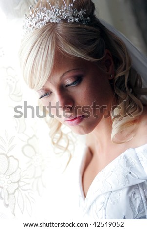 Portrait of pretty young blond haired adult bride with tiara looking down.