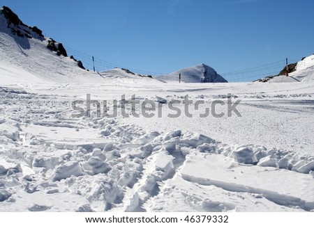 Closeup of ski tracks in snowy Alpine mountainous landscape.