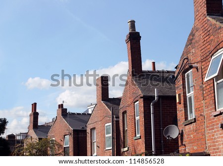 Back of English red brick terraced houses in city with blue sky background and copy space.