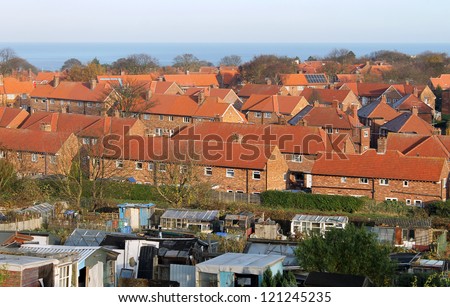 Traditional English red brick housing estate with allotment buildings in foreground, Scarborough, North Yorkshire, England.