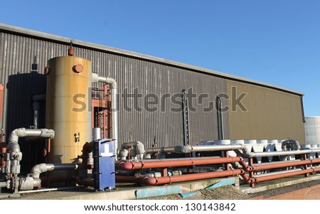Exterior of modern industrial factory building with tank and pipes.