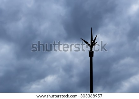 Silhouette Lightning Rod against Dark Clouds