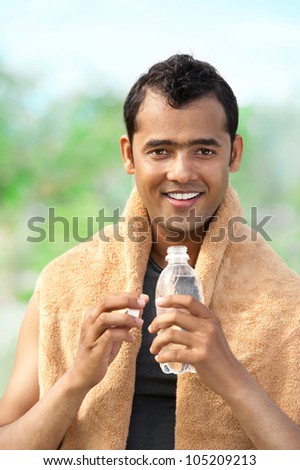 Happy Asian man with plastic bottle looking at camera
