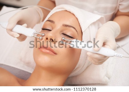 Young client of cosmetic salon having relaxing procedure on her face with special devices