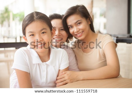 Beautiful little girl sitting and looking at camera with her family behind