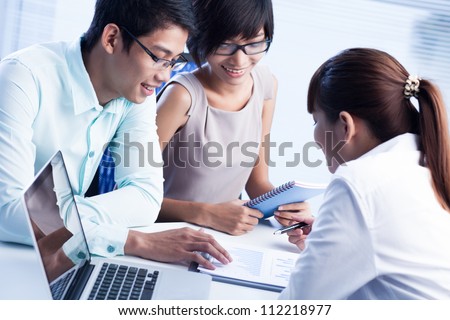 Business team of three discussing possible strategic movements based on the latest statistics Business team of three discussing possible strategic movements based on the latest statistics