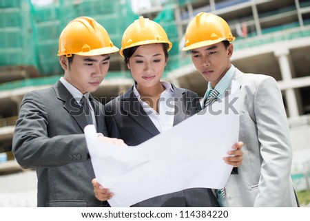 Group of architects being busy studying blueprint