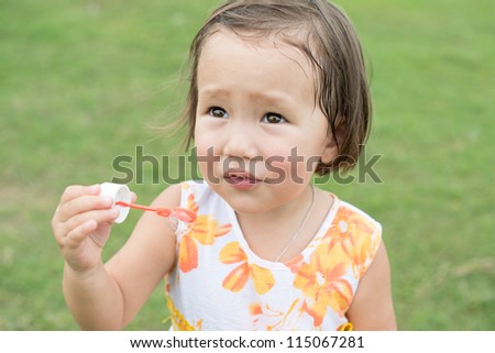 Cute girl blowing soap bubbles on a summer day