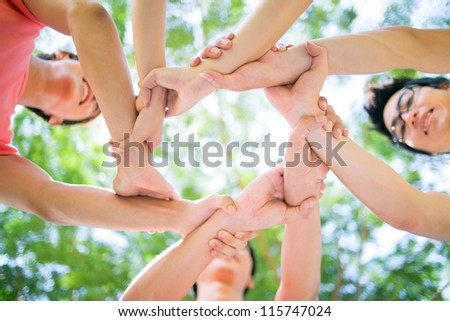 Close-up of hands of young people joined in a circle