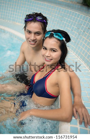 Vertical portrait of a smiling couple sitting in hot whirlpool