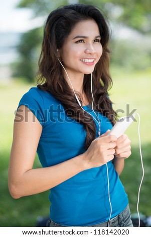 Vertical shot of a cheerful girl enjoying music on a nice summer day